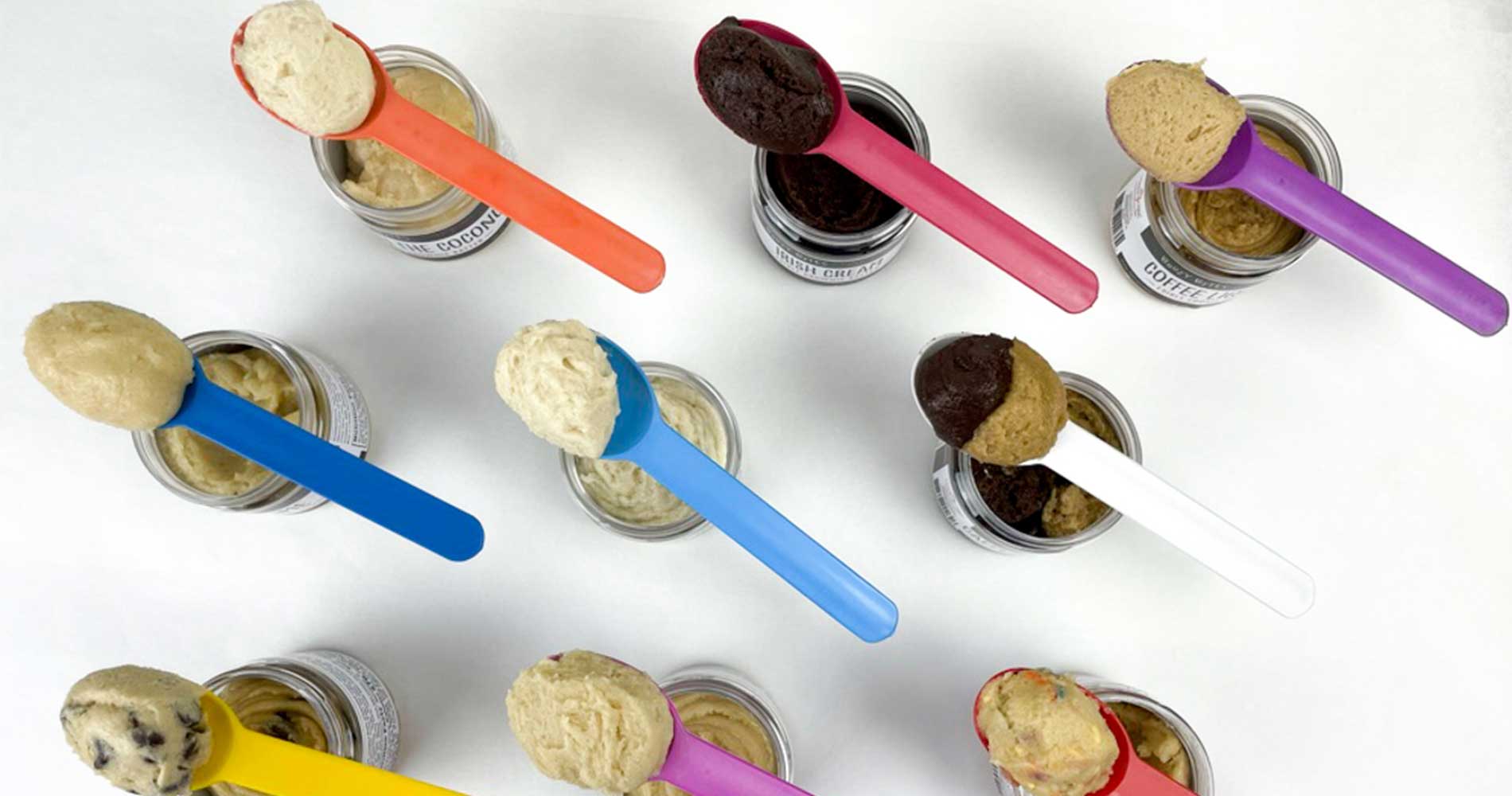 Overhead All flavors of Edible Cookie Dough with dough in spoons